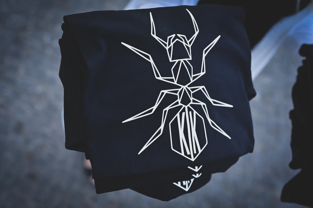 Blacksunset mustad T-särgid geomeetrilise sipelga trükiga – virnas; valge line-art front-print, detailne graafika.