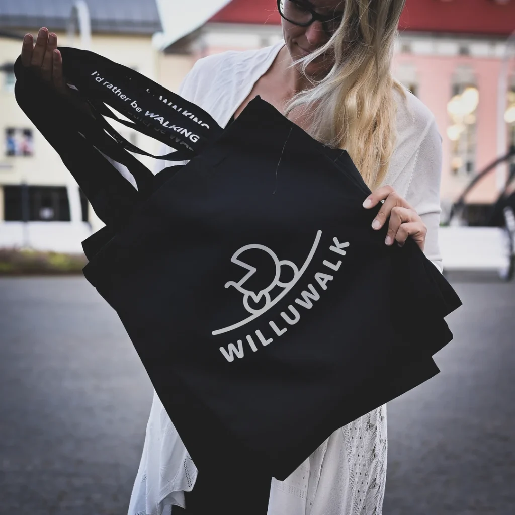 Blacksunset must tote WILLUWALK logoga – inimene hoiab kotti; urban lifestyle, selge valge front-print tellimustöö.