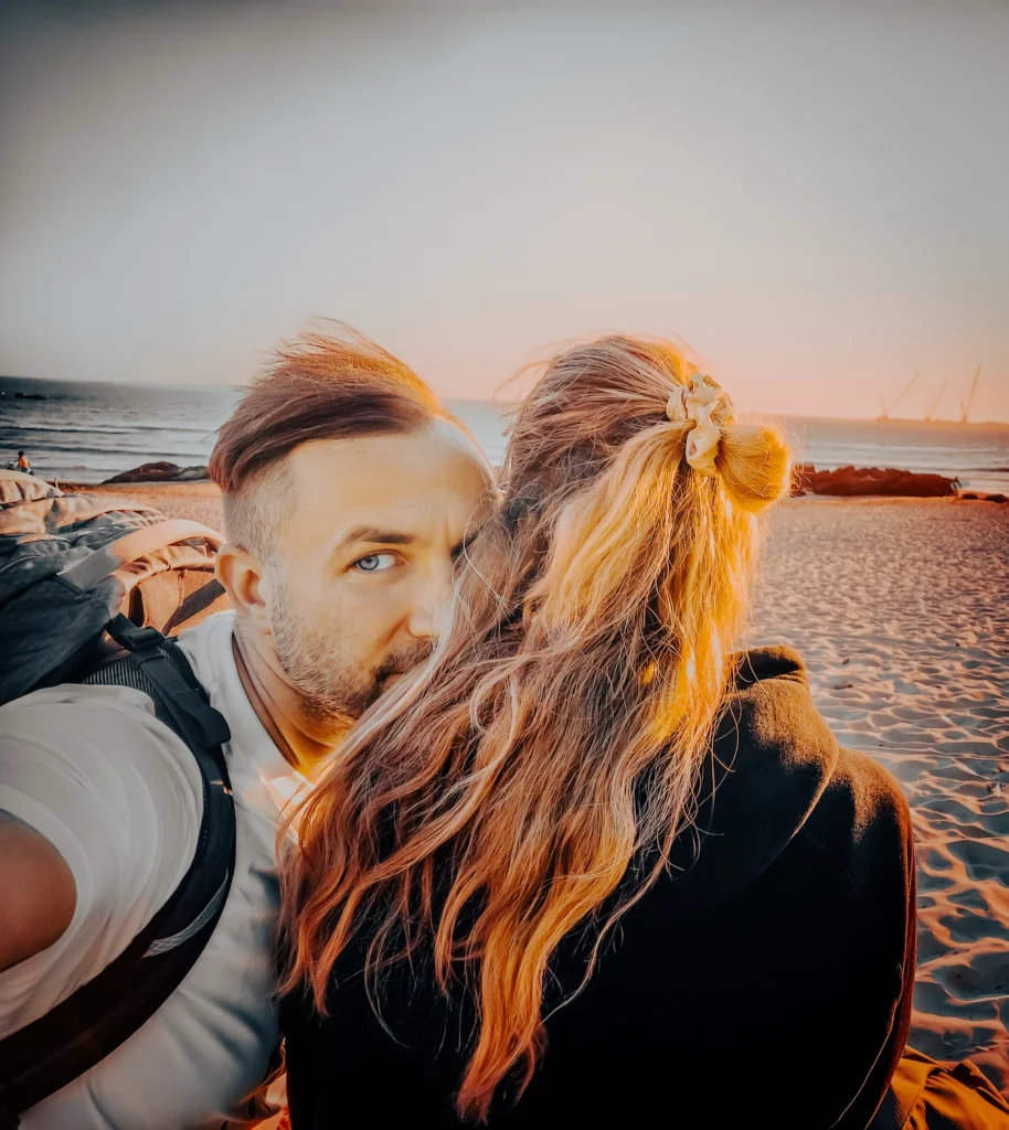 Paar rannal kuldses loojangus; lähiplaan õlg-õla kõrval – soe toon ja vabaaja meeleolu, Blacksunset lifestyle.