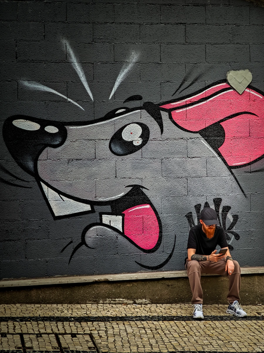 Tänavakunst: suur hiire seinamaaling südamega; inimene istub all serval – urban lifestyle-kaader Blacksunset portfoolios.