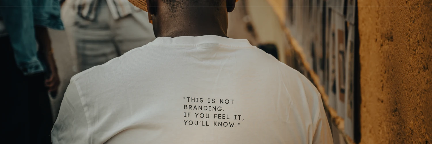 Valge T-särk seljalt vaates tekstiga “THIS IS NOT BRANDING. IF YOU FEEL IT, YOU’LL KNOW.” – minimalismi ja sõnumi rõhutav lifestyle-kaader.