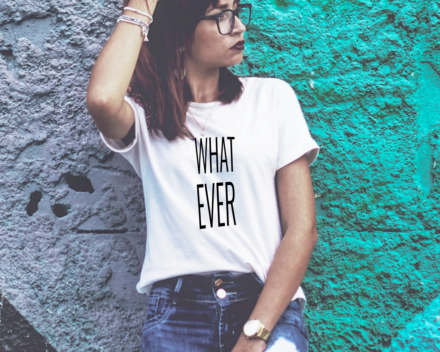 Blacksunset valge statement-t-särk kirjaga WHAT EVER, türkiissel urban seinataustal; minimalistlik hoiak – ütle vähem, mõju rohkem.