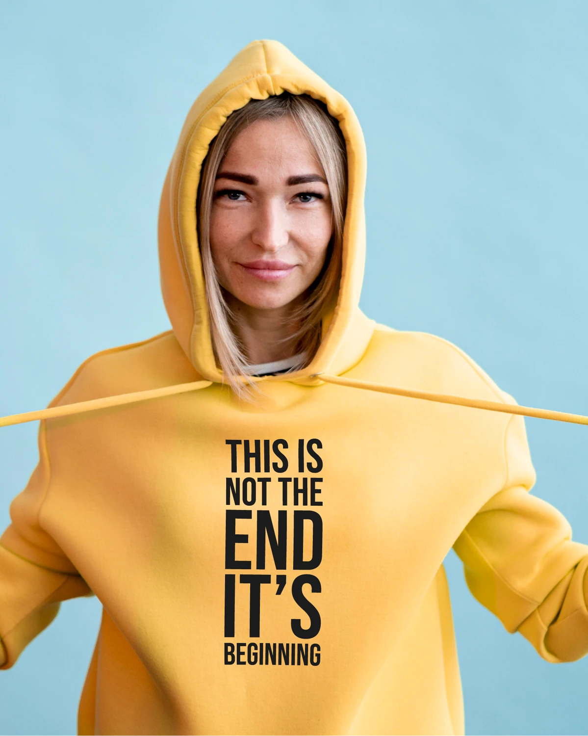 Kollane kapuutsikas tekstiga “THIS IS NOT THE END IT’S BEGINNING” – stuudiopilt; kontrastne must front-print, kampaania visuaal.