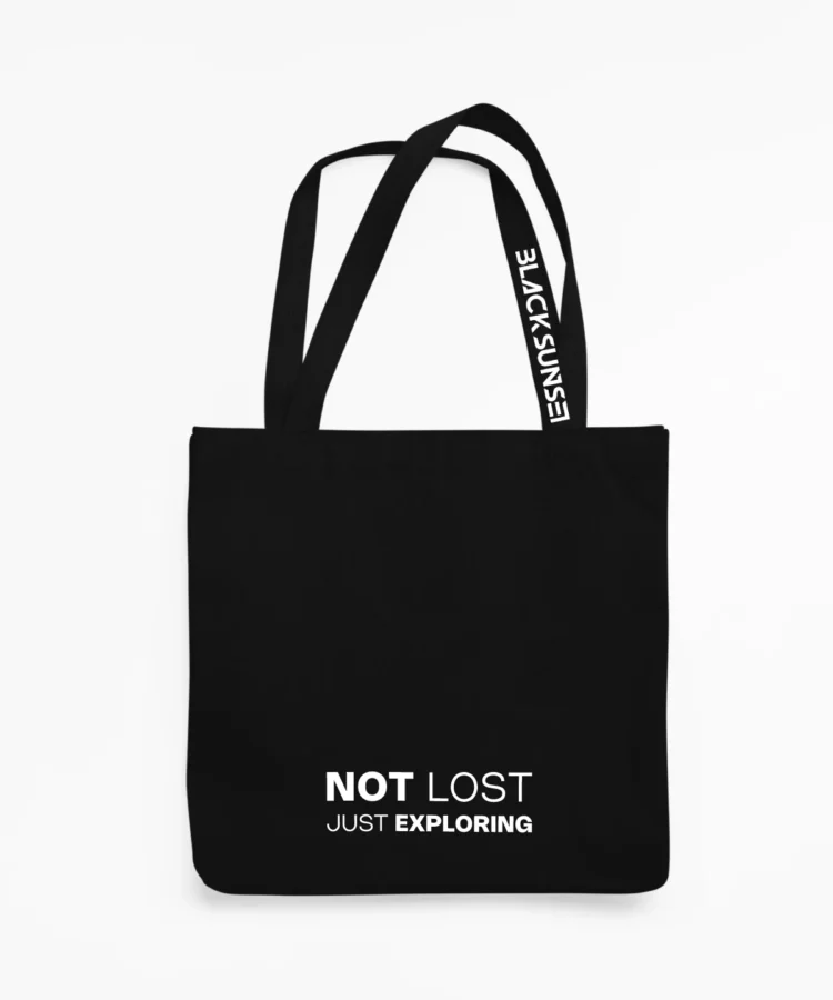 Must BLACKSUNSET kangaskott valge kirjaga “NOT LOST — JUST EXPLORING”, minimalistlik ja vastupidav igapäevaseks kandmiseks.