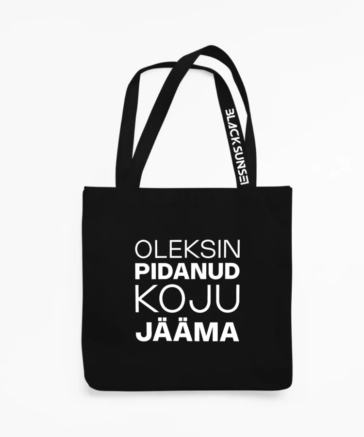 Must kangaskott suure valge kirjaga “OLEKSIN PIDANUD KOJU JÄÄMA”, eestvaade; minimalistlik disain, pikad sangad, sangal Blacksunset’i kiri.