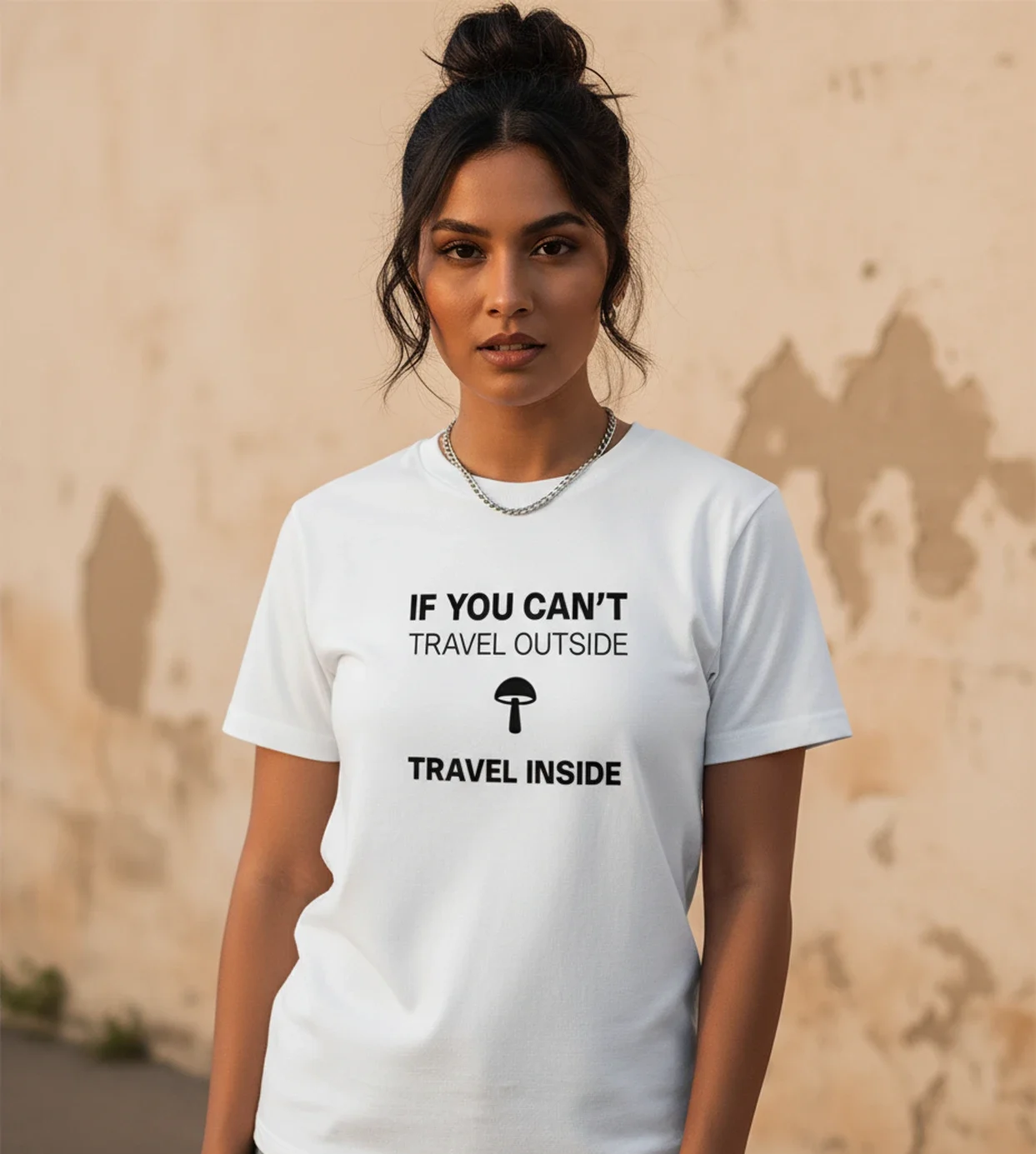 Blacksunset valge unisex T-särk „IF YOU CAN’T TRAVEL OUTSIDE / TRAVEL INSIDE”; sirge eesvaade, must kiri ja seenesümbol, beež seintaust.