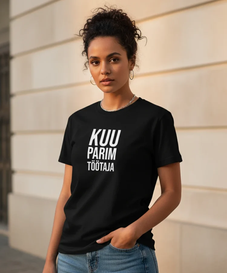 Blacksunset unisex must T-särk „KUU PARIM TÖÖTAJA”; valge vertikaalne tekst; naismudel ¾ vaates, linnatänav ja hele tellissein taustal.
