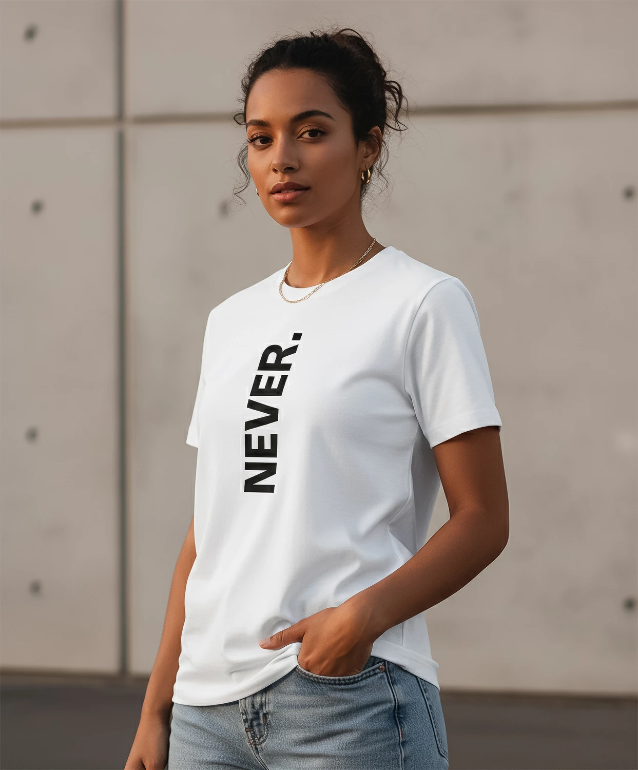 Blacksunset unisex valge T-särk „NEVER.” — vertikaalne must tekst, minimalistlik stiil; naismudel, 3/4 eesvaade, betoonseina taust.