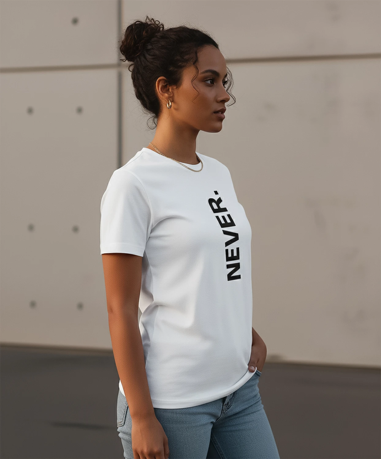 Blacksunset unisex valge T-särk „NEVER.” — vertikaalne must tekst; naismudel vasakult profiilis, puhas lõige, pehme langus, betoonsein.