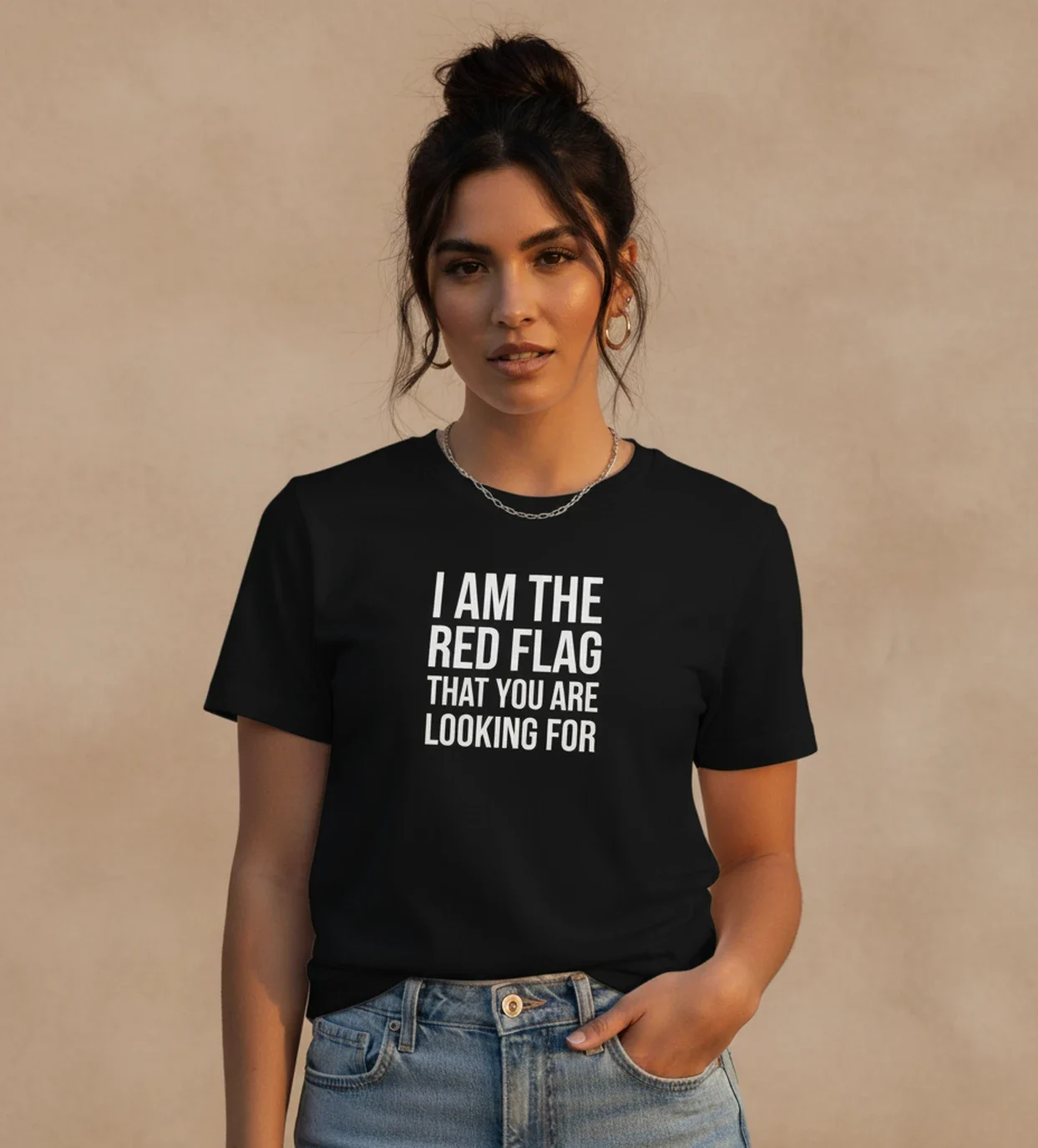 Blacksunset unisex must T-särk “I AM THE RED FLAG THAT YOU ARE LOOKING FOR”; naismudel ¾ eesvaade, valge kiri, soe õhtuvalgus, neutraalne sein.