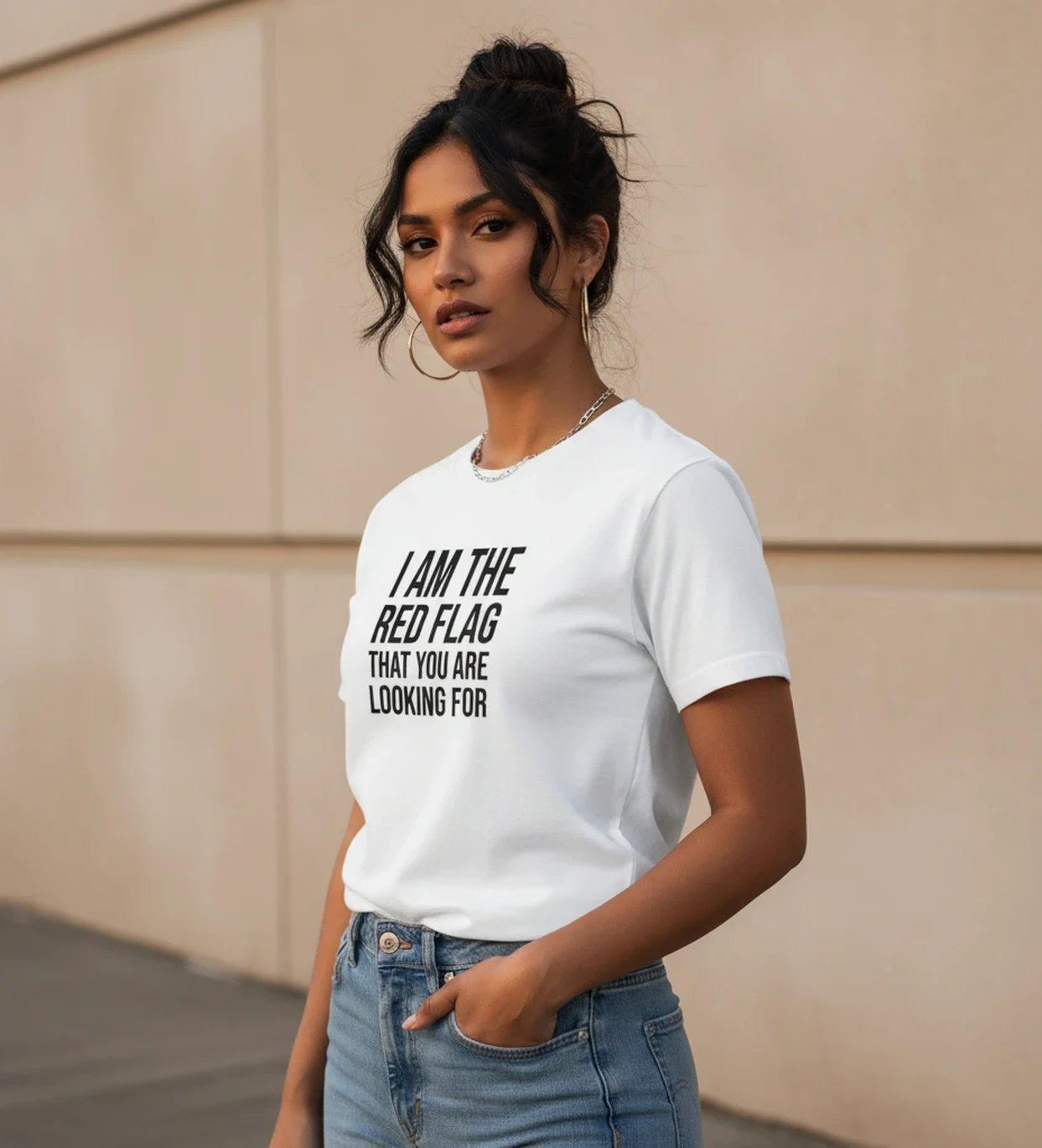 Blacksunset unisex valge T-särk “I AM THE RED FLAG THAT YOU ARE LOOKING FOR”; ¾ vaade, must kiri, beež modern sein, käsi taskus.