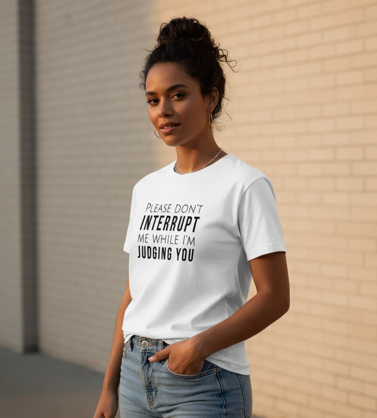 Blacksunset unisex valge T-särk PLEASE DON'T INTERRUPT ME WHILE I'M JUDGING YOU — must tüpograafia; naismudel 3/4 eesvaade, hele tellissein.