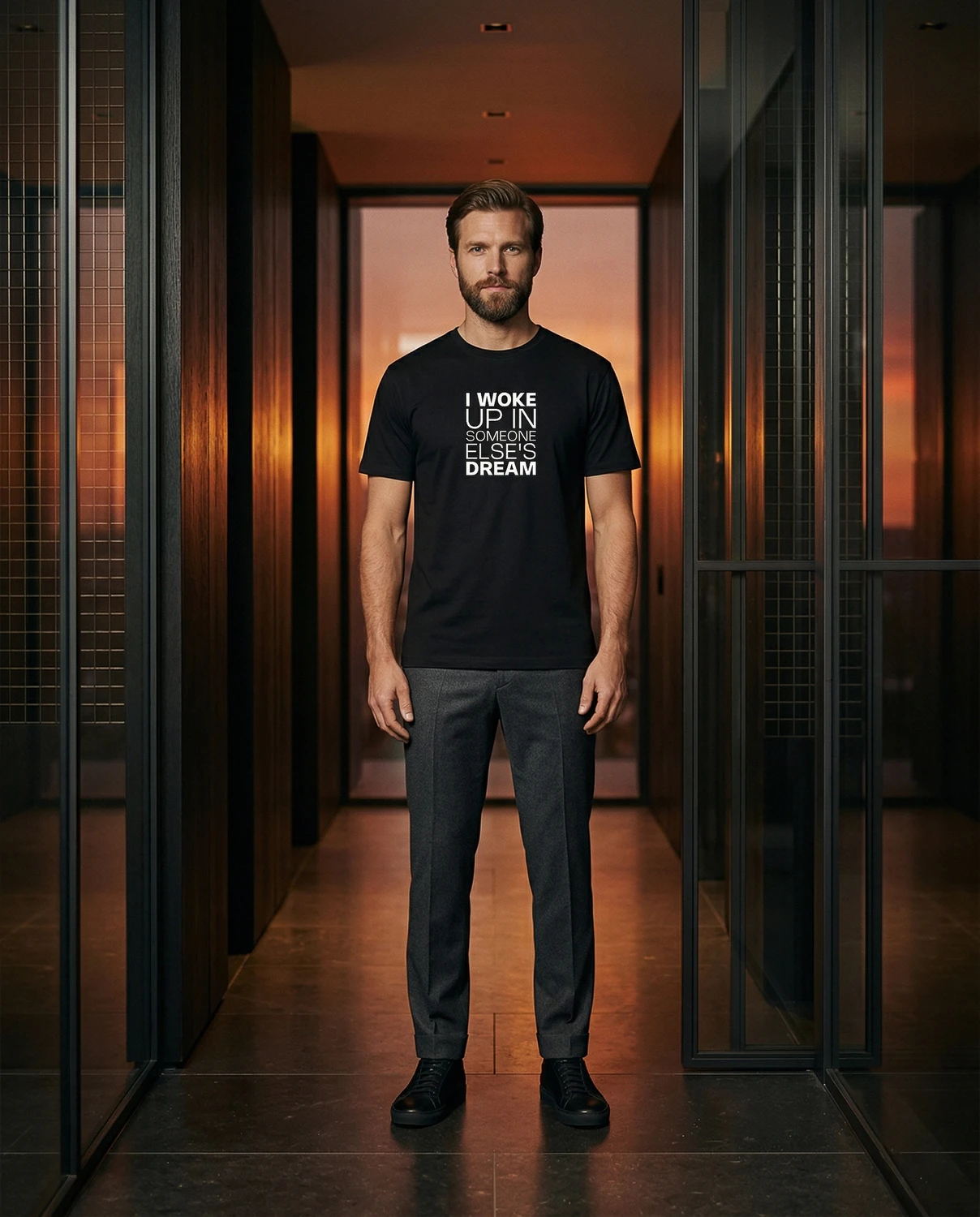 A man wears a black I Woke Up In Someone Else's Dream T-shirt in an evening interior