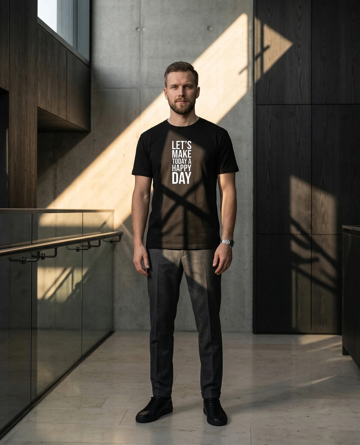 A man wears a black Let's Make Today a Happy Day T-shirt in a modern interior