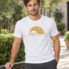 Rasmus wears a white unisex T-shirt with the gold Mitte täna hedgehog beside a city garden bench.