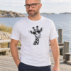 Mees valges Black Giraffe Unisex T-särgis ja tumesinistes pükstes mereäärsel laudteel.
