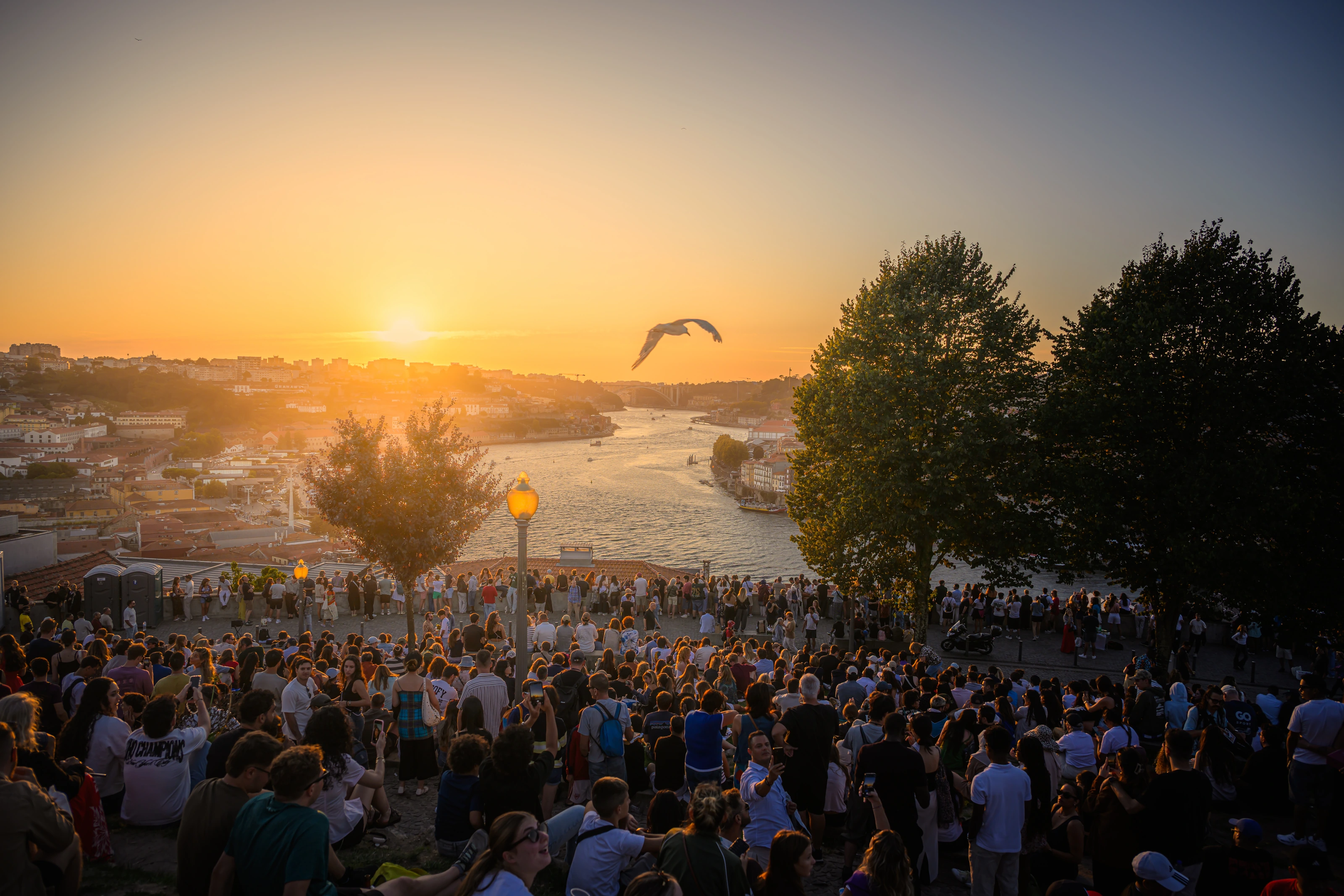 Päikeseloojang Porto kohal, inimesed vaatavad jõele avanevat vaadet.