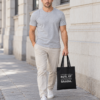 Rasmus carries a black tote bag on a city street, with grey Estonian text “Ostsin selle koti, et dopamiini saada.”