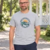 Anti kannab hallmelanži Pärnu Surf Social Clubi linnakujundusega T-särki suvises pargis heleda paviljoni kõrval.